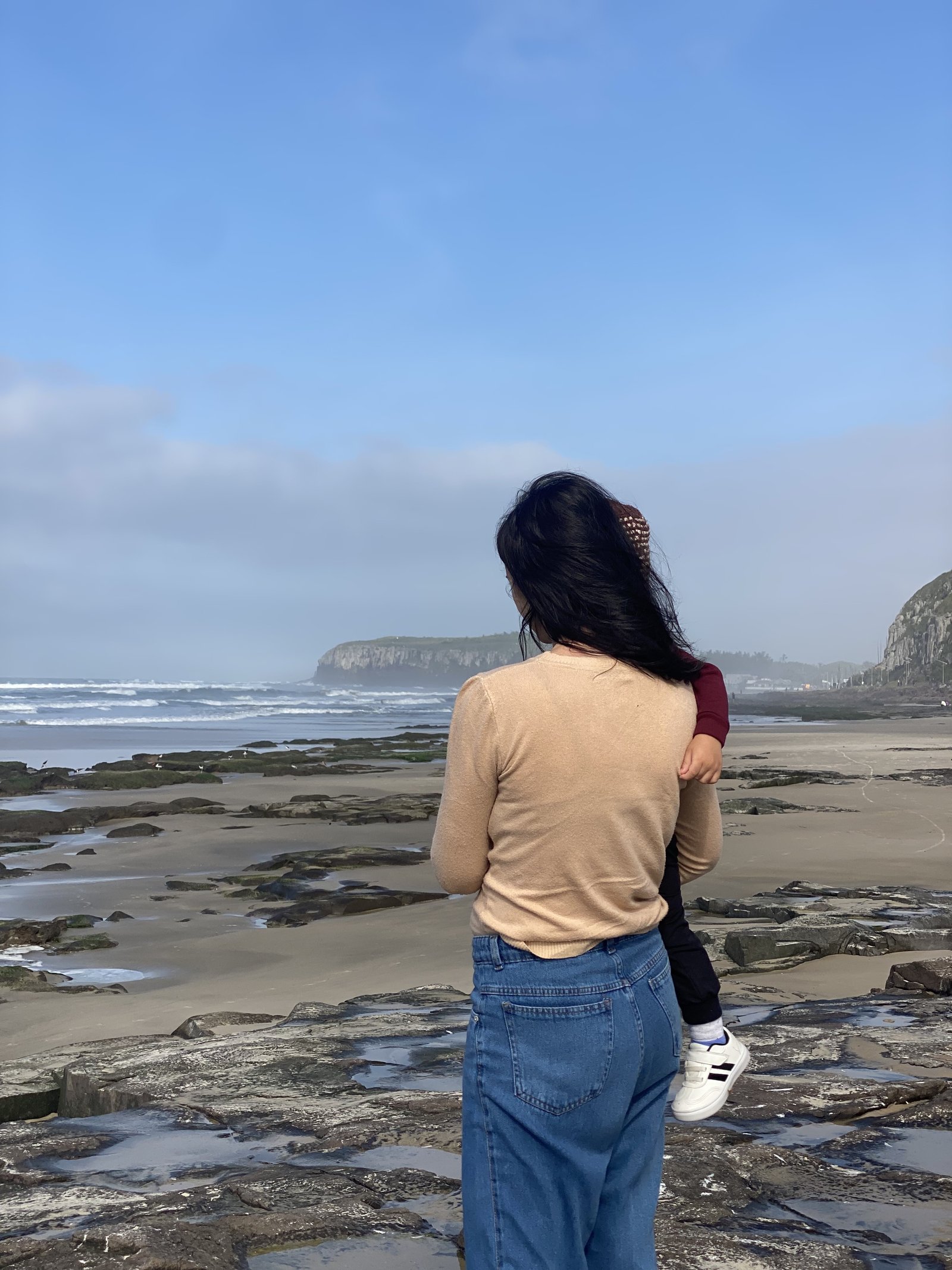 Mulher e criança contemplando a praia